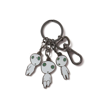 A multicharm keychain featuring three cartoon-style Kodama figures from the movie Princess Mononoke, with a black nickel finish and UV glow details.